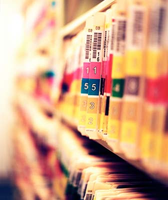 A close-up view of stacked paper dental charts featuring diagrams of teeth and clinical notes.