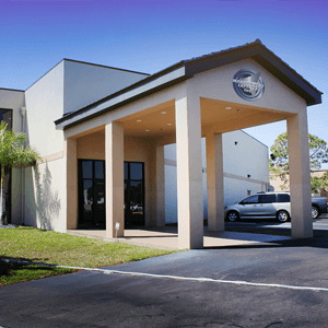 A modern multi-story office building with glass windows and landscaped surroundings in Florida.