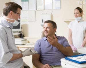 A dentist and patient engaged in conversation in a dental office.