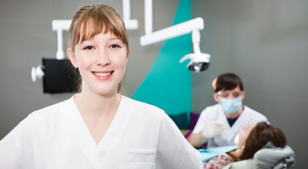 A dental hygienist performing a teeth cleaning on a patient in a dental office.