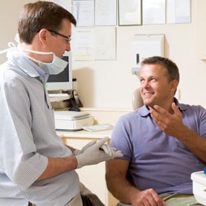 A dentist and a patient interacting in a consultation room.