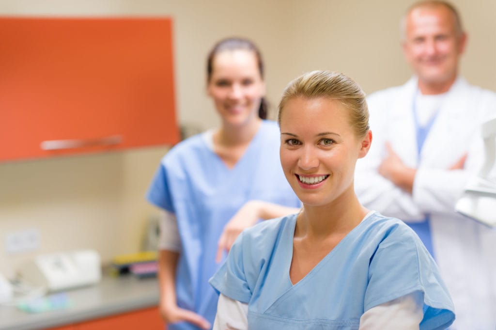 A smiling group of medical professionals standing together in a surgery room.