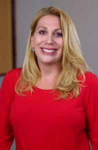Professional portrait of Dr. Leslie Pasco, a female dentist in business attire.