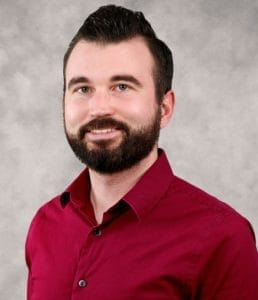 Professional headshot of a smiling man in business attire.