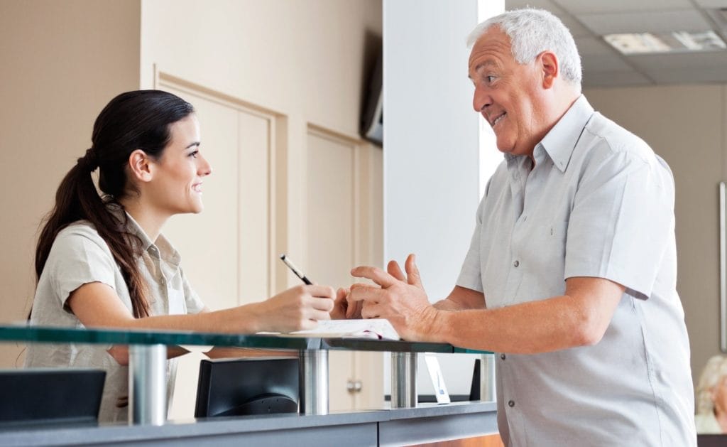A friendly dental receptionist smiling at the reception area.