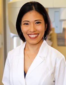 Portrait of Dr. Justene Doan, a smiling female dentist in professional attire.