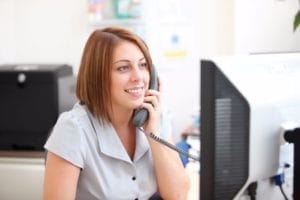 A smiling dental receptionist at the front desk.