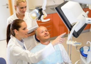 A dentist consulting with a patient in an examination room.