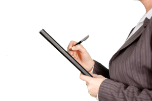 A person writing notes at an official desk in an office.