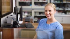 A dental office manager seated at a desk with computer.