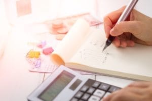 Blurred close-up of accounting documents, calculator, and pen on a wooden desk.