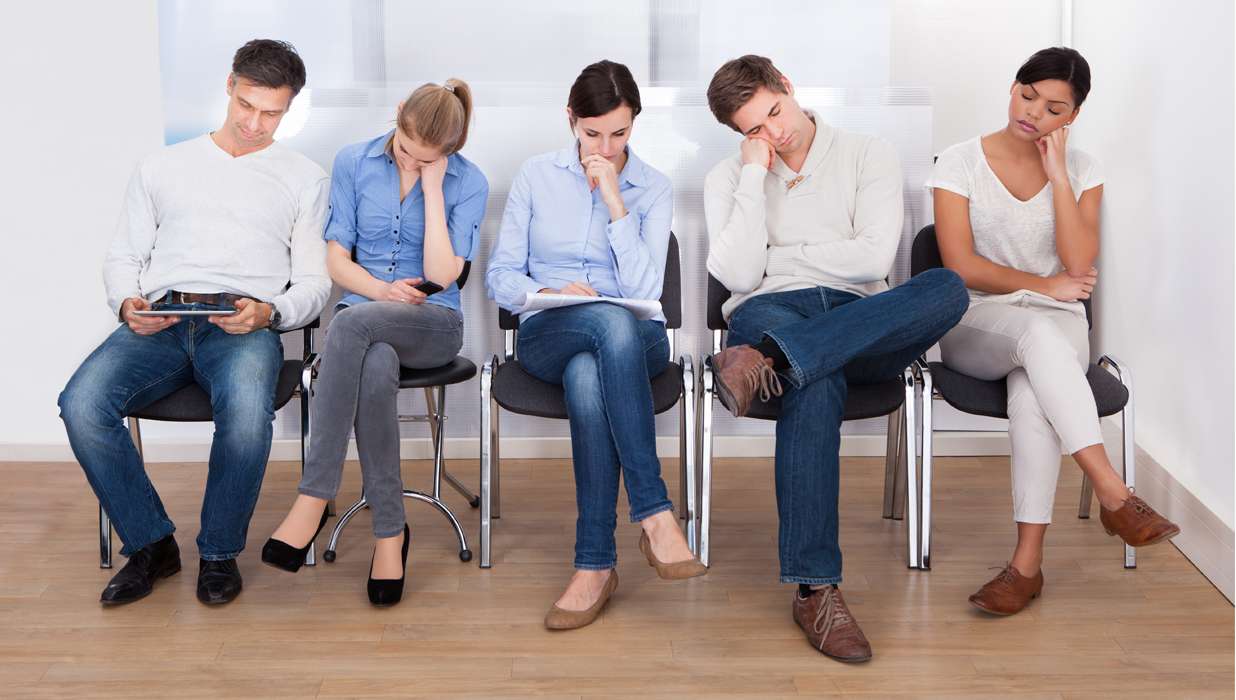Patients seated uncomfortably in a waiting room of a healthcare facility.