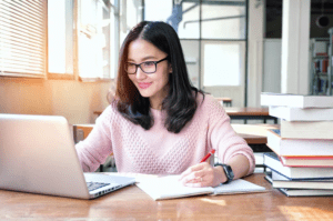 A person studying marketing materials at a desk with a laptop.