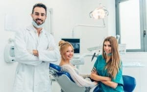 Stock image of a busy dental office with patients waiting and staff attending to them.