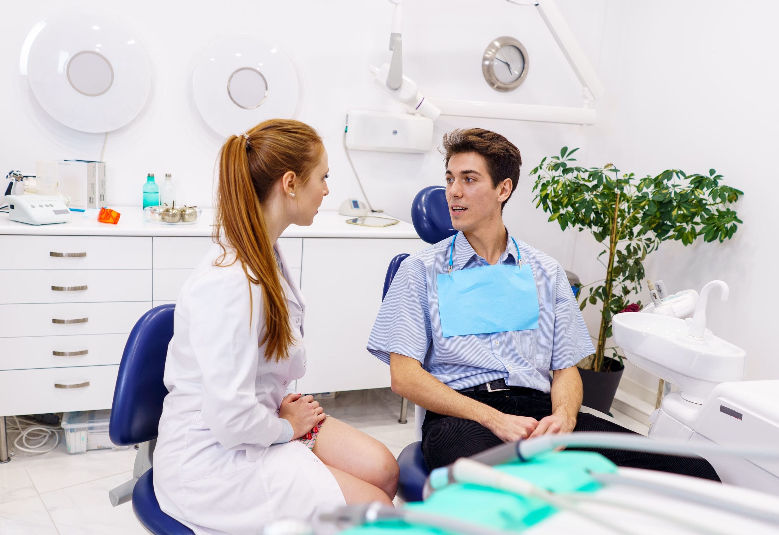 Dentist talking to patient in the dental exam chair.
