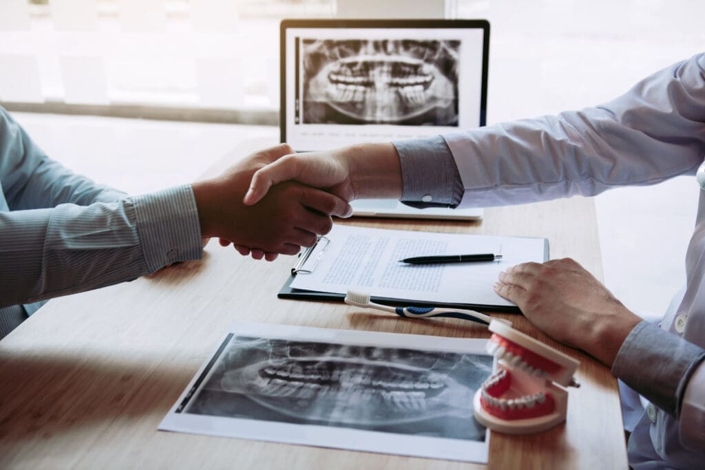 Dentist and patient shaking hands on a treatment plan