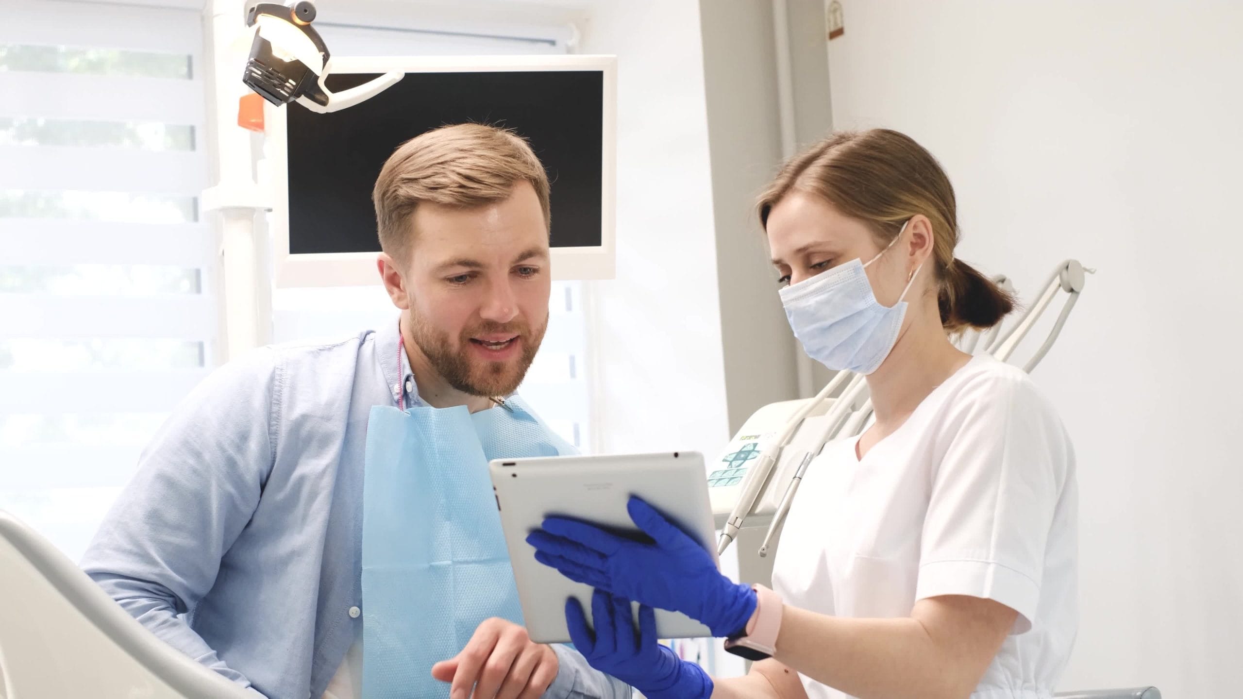 A dentist discussing treatment with a seated patient in a dental clinic.