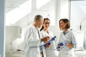 A team of smiling healthcare workers clapping in appreciation during a meeting.
