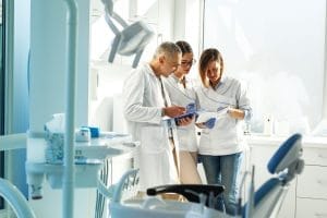 A stressed dentist sitting at a desk in a modern dental office, reviewing paperwork with a concerned expression.