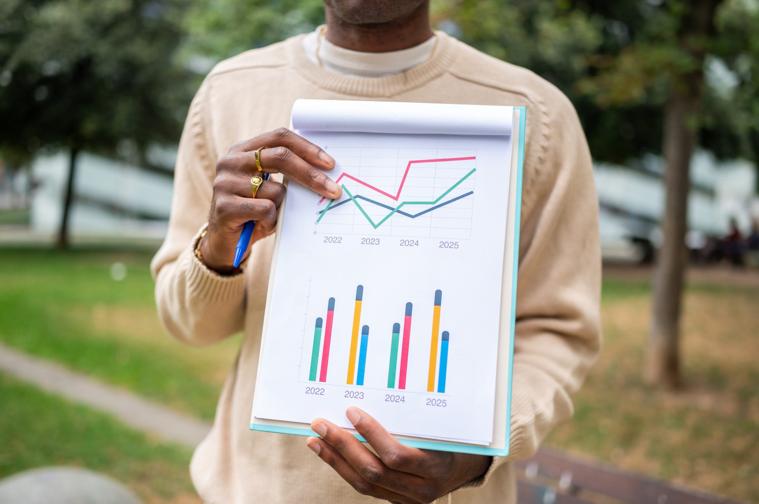 Person holding a paper with a pie chart and bar charts.