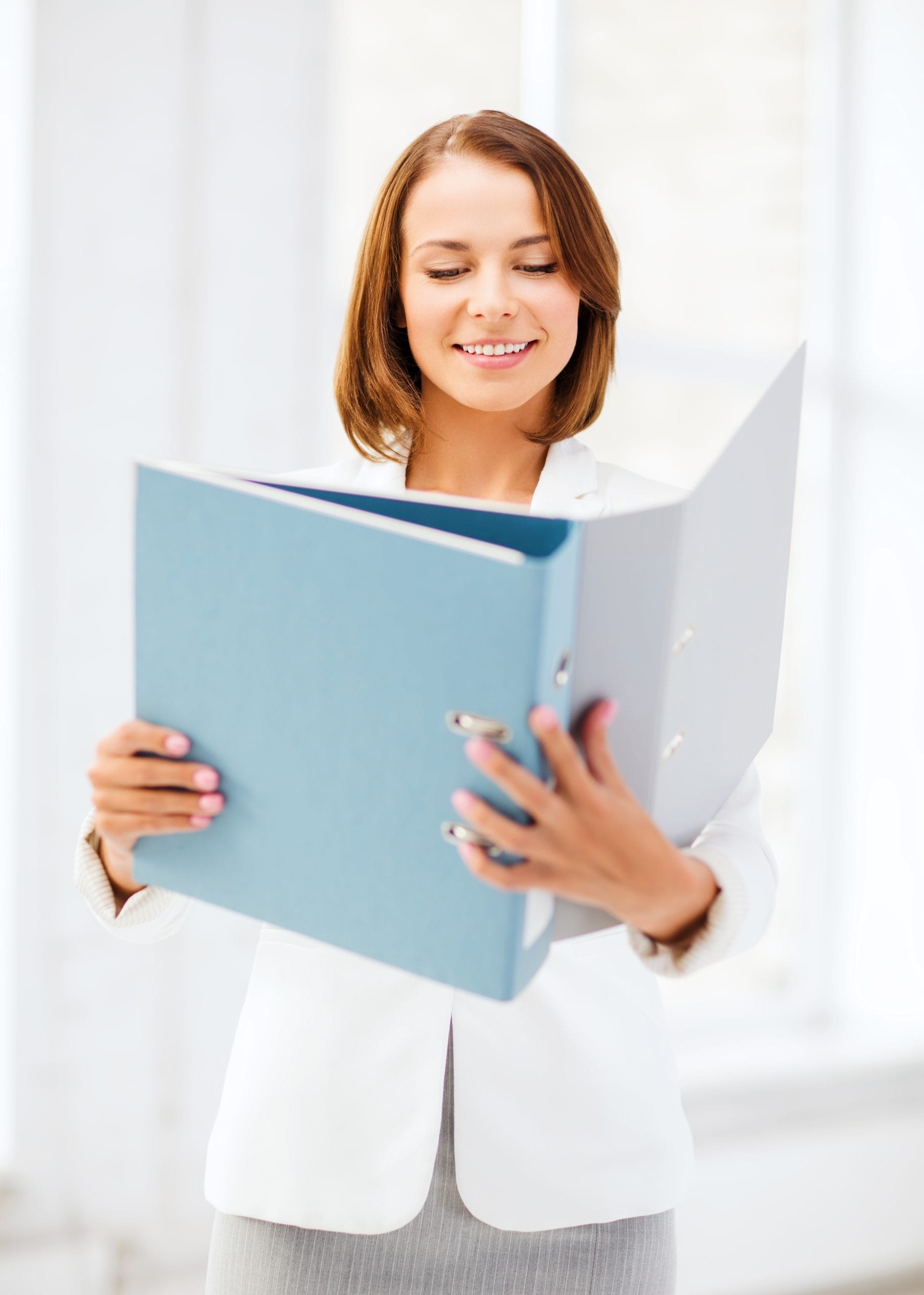 Woman holding a blue binder, in a professional work setting.