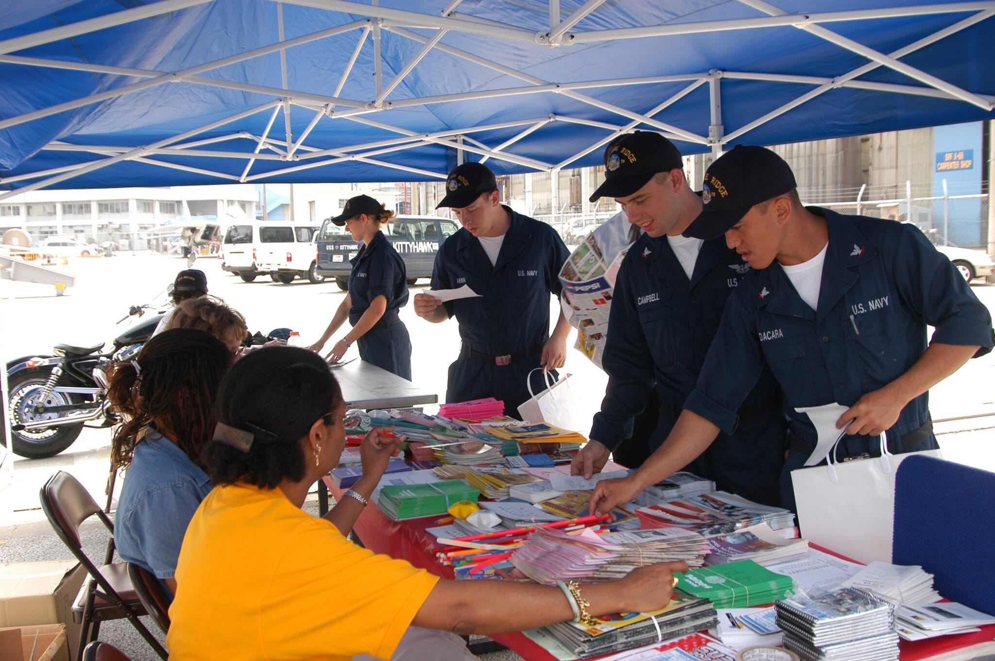 Sailors receiving informational materials on healthy lifestyles at a naval health fair event.